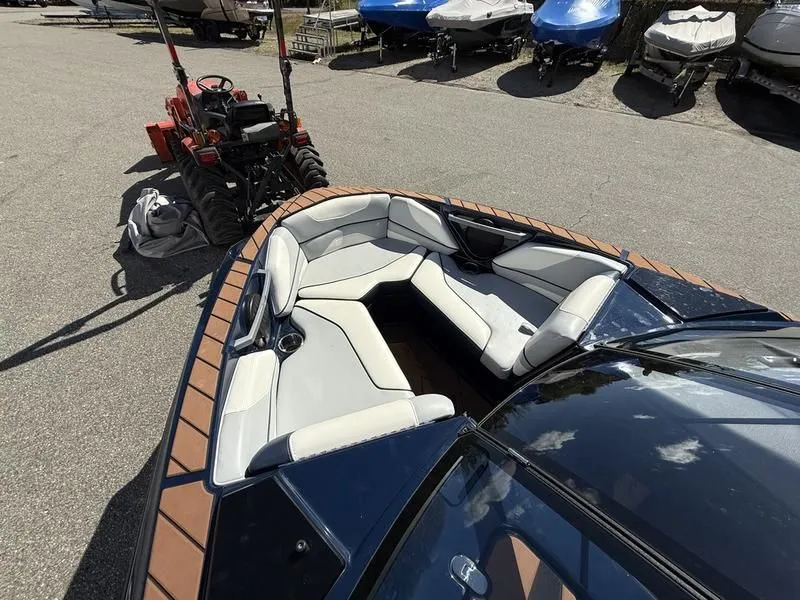 Slide: The Image of 2024 Malibu TXi boat with luxurious interior, parked next to tractor. - 20
