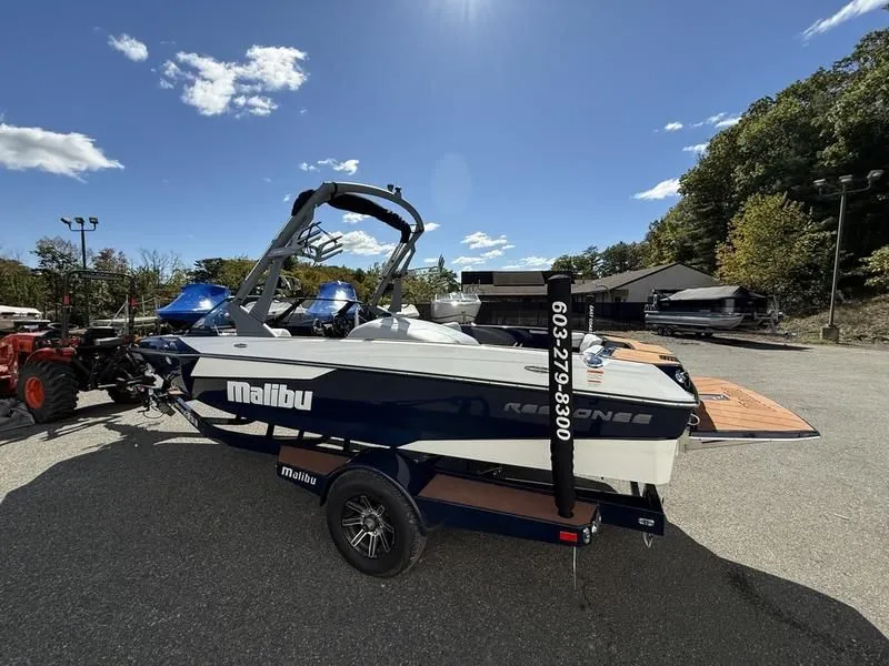 Slide: The Image of 2024 Malibu TXi boat on trailer under sunny skies. - 4