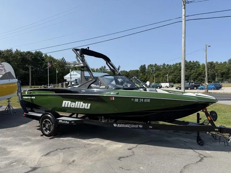 The Image of Green 2022 Malibu TXi boat parked on trailer outdoors. - 1