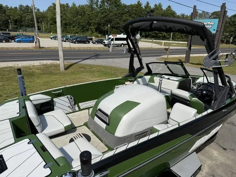 Slide: The Image of 2022 Malibu TXi boat with green and white interior on a parking lot. - 10