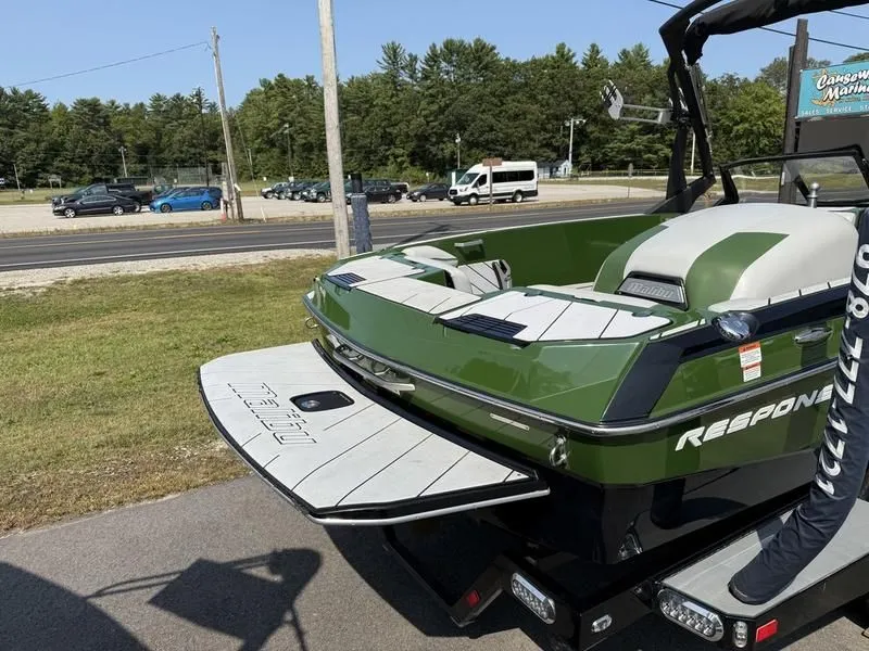 Slide: The Image of Green 2022 Malibu TXi boat parked outdoors. - 20