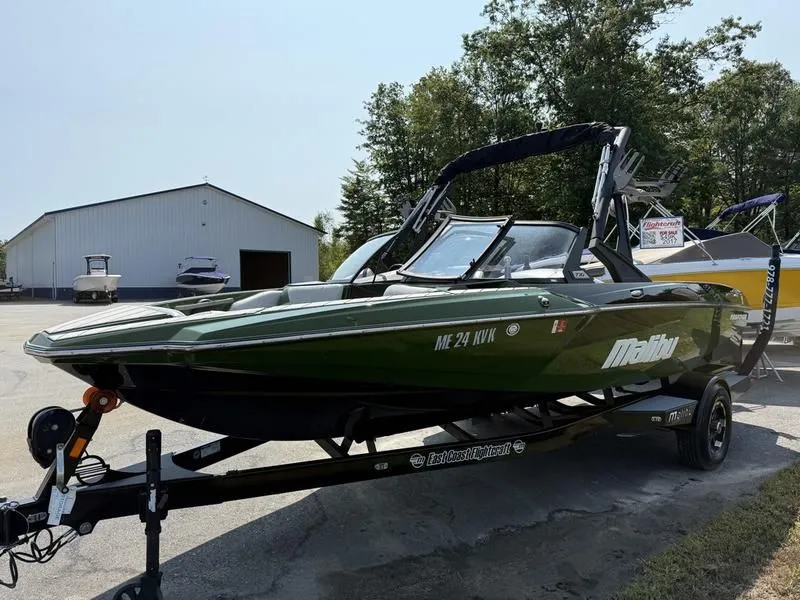 Slide: The Image of Green 2022 Malibu TXi boat on trailer in front of warehouse. - 4
