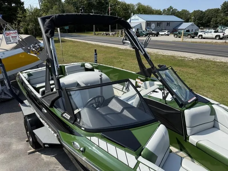 Slide: The Image of Green 2022 Malibu TXi boat parked outdoors. - 6