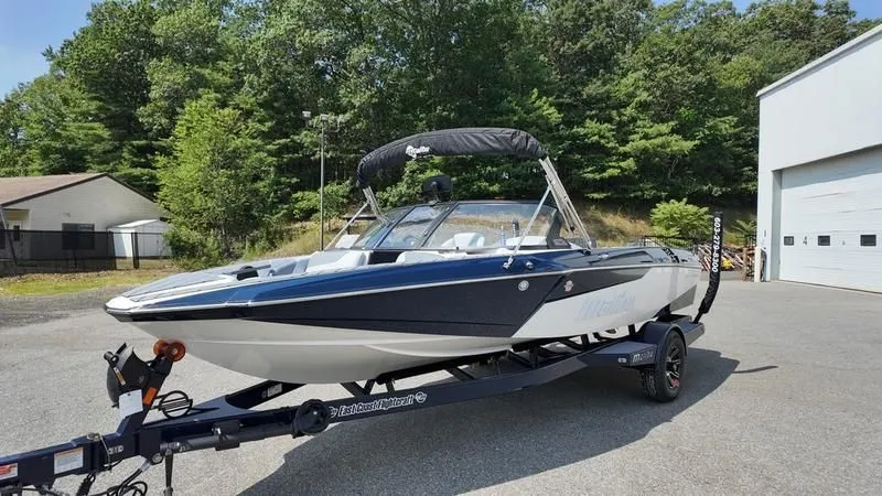 Slide: The Image of 2025 Malibu TXi boat on trailer in front of building. - 3