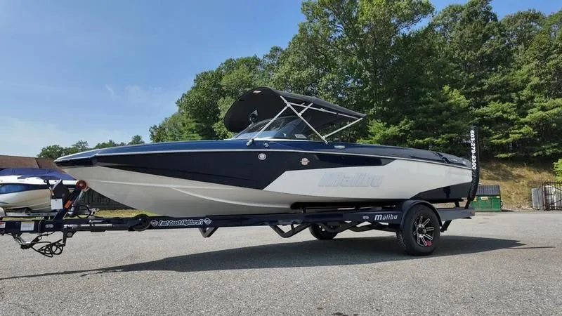 Slide: The Image of 2025 Malibu TXi boat parked on trailer outdoors. - 6