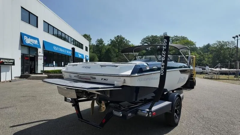 Slide: The Image of 2025 Malibu TXi boat on trailer in front of a building. - 8