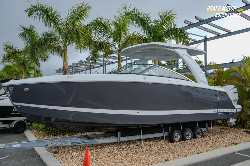 Slide: The Image of 2026 Four Winns H9 OB boat on trailer, surrounded by palm trees. - 10
