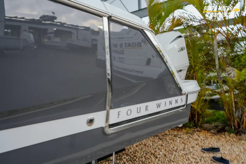 Slide: The Image of 2026 Four Winns H9 OB boat, sleek design, parked outdoors near palm trees. - 14