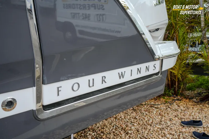 Slide: The Image of 2026 Four Winns H9 OB boat rear view with logo, displayed outdoors. - 16