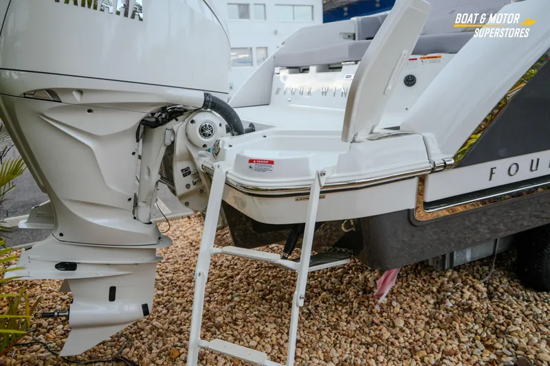 Slide: The Image of 2026 Four Winns H9 OB boat with outboard motor and swim ladder on gravel. - 24