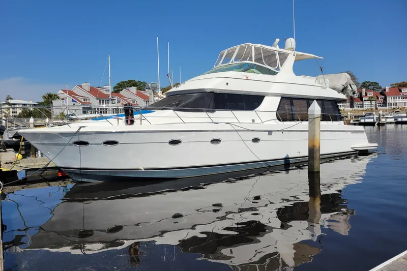 The Image of 2001 Carver 570 Voyager Pilothouse yacht docked at marina, reflecting on calm water. - 0