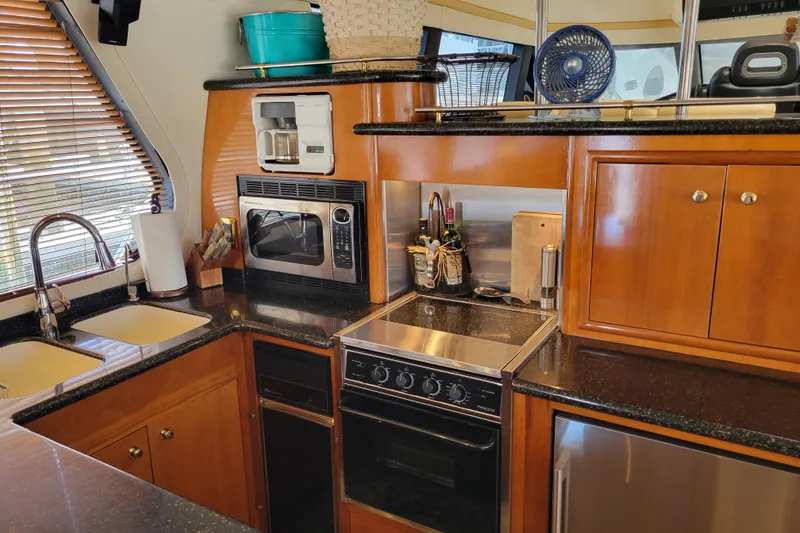 Slide: The Image of Kitchen area of 2001 Carver 570 Voyager Pilothouse with modern appliances and wooden cabinetry. - 10