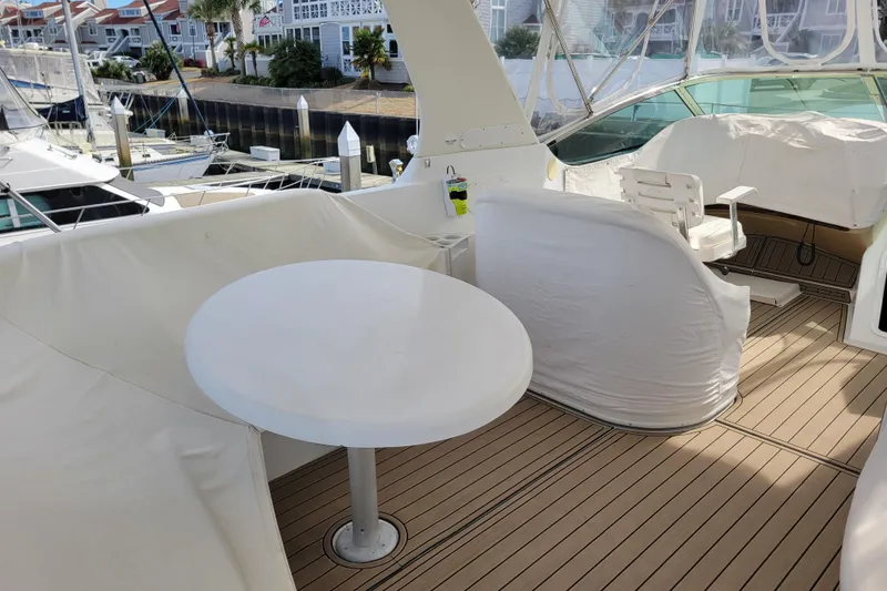 Slide: The Image of 2001 Carver 570 Voyager Pilothouse yacht deck with seating and table, docked at marina. - 123