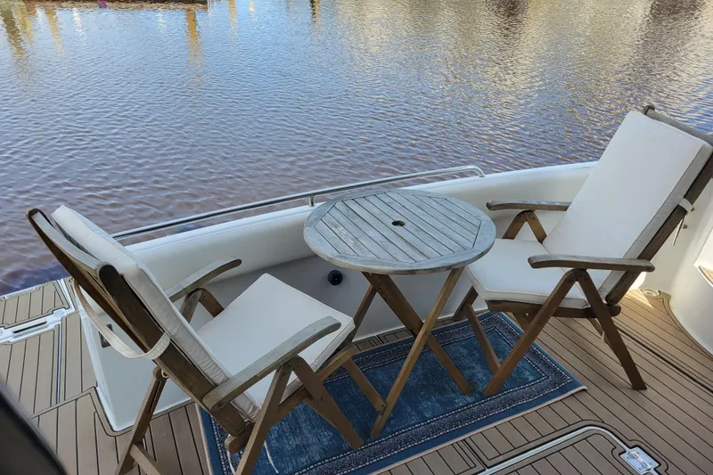 Slide: The Image of Deck seating area on 2001 Carver 570 Voyager Pilothouse with chairs and table by the water. - 154