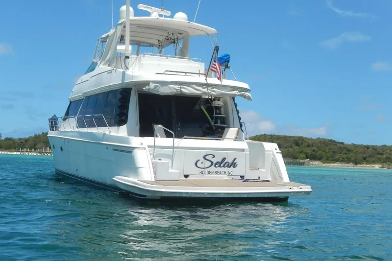 Slide: The Image of 2001 Carver 570 Voyager Pilothouse yacht on serene blue waters near a lush shoreline. - 160