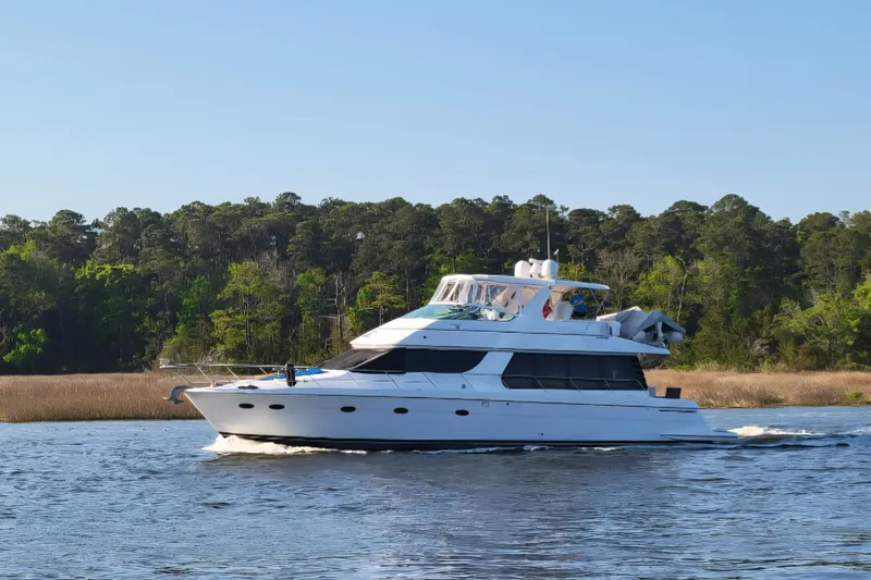 Slide: The Image of 2001 Carver 570 Voyager Pilothouse yacht cruising on a scenic river with forested backdrop. - 162