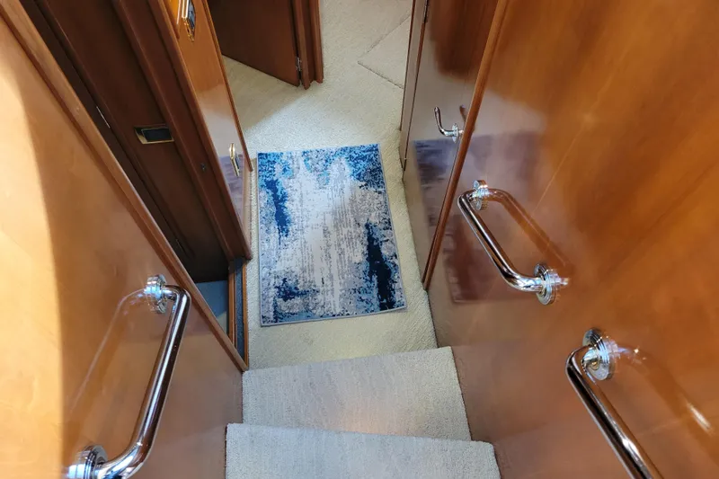 Slide: The Image of Staircase inside 2001 Carver 570 Voyager Pilothouse with wooden walls and blue rug. - 50