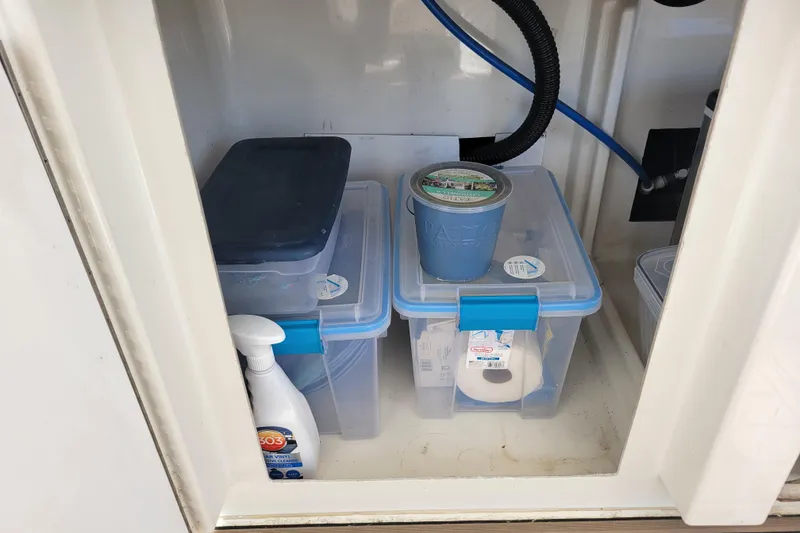 Slide: The Image of Storage compartment on a 2001 Carver 570 Voyager Pilothouse with plastic containers and cleaning supplies. - 84