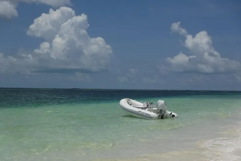 Slide: The Image of Inflatable boat on turquoise water near sandy beach under cloudy sky. - 86