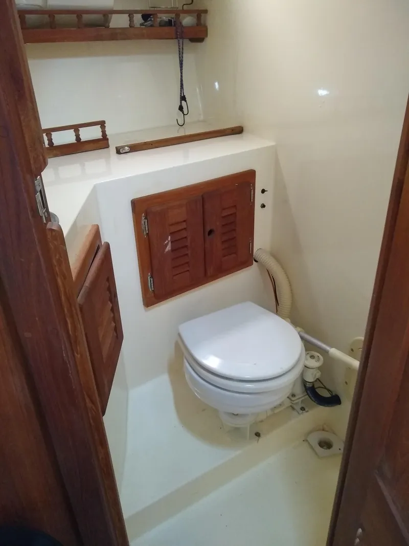 Slide: The Image of 1988 Albemarle 27 Express Fisherman boat bathroom with wooden cabinets and white toilet. - 24