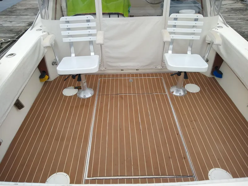 Slide: The Image of 1988 Albemarle 27 Express Fisherman boat deck with two white chairs and wooden flooring. - 8