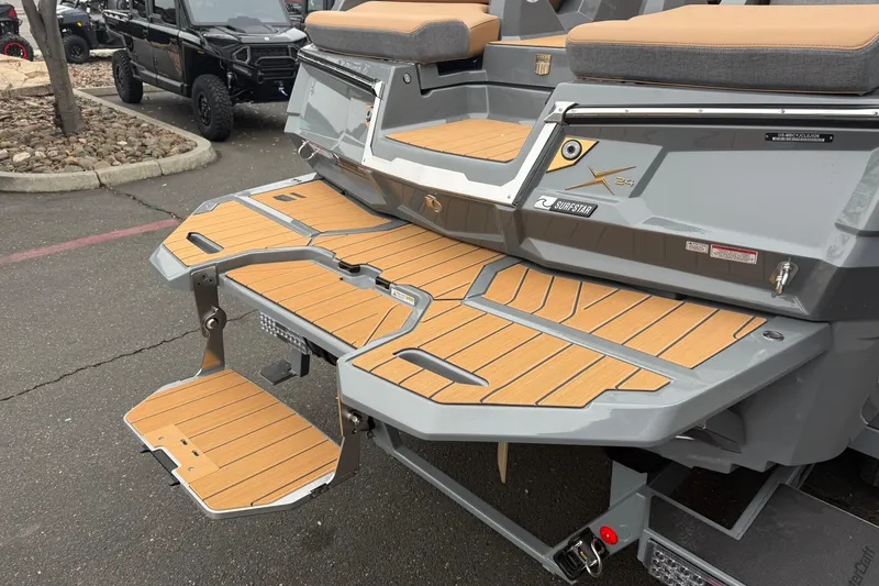 Slide: The Image of 2026 MasterCraft X24 boat with teak swim platform and gray seating. - 13