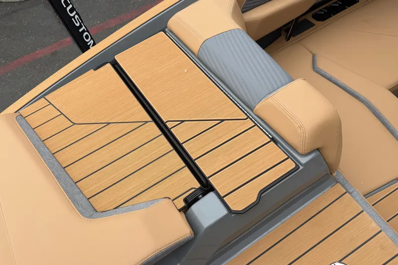 Slide: The Image of 2026 MasterCraft X24 boat interior with tan and gray seating and wood-style flooring. - 19