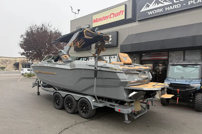 Slide: The Image of 2026 MasterCraft X24 boat on trailer outside dealership, showcasing sleek design and luxury features. - 2