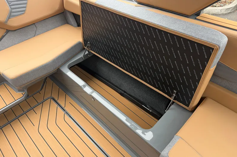 Slide: The Image of 2026 MasterCraft X24 boat interior storage compartment with tan and gray seating. - 70
