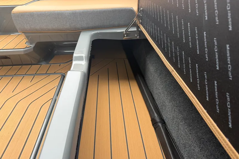 Slide: The Image of 2026 MasterCraft X24 boat interior with tan and gray seating, showcasing storage compartment. - 71