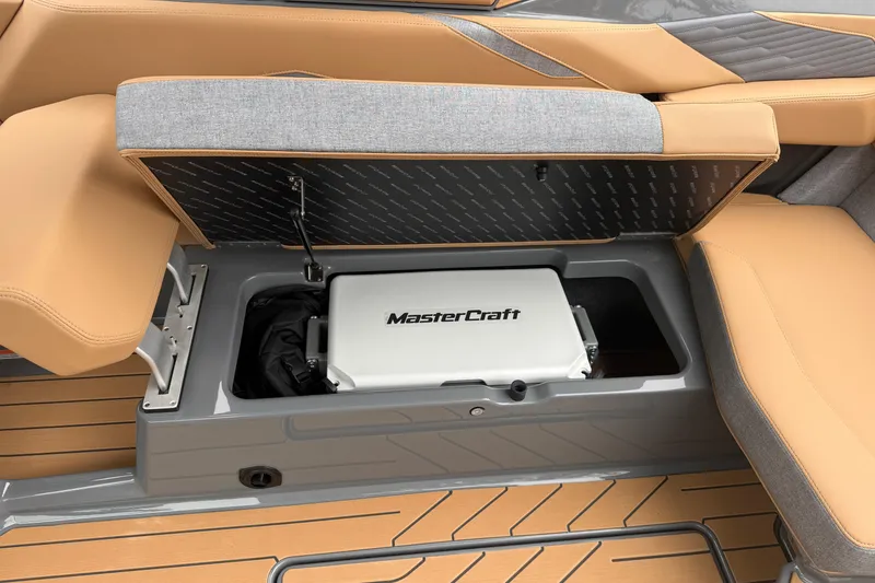 Slide: The Image of 2026 MasterCraft X24 boat storage compartment with tan and gray seating. - 72