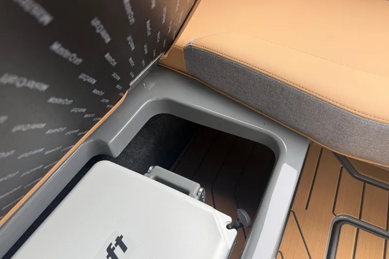 Slide: The Image of 2026 MasterCraft X24 boat interior with tan and gray seating, storage compartment. - 73