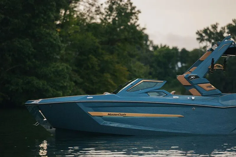 Slide: The Image of Manufacturer Provided Image: 2026 MasterCraft X24 boat on a serene lake with lush green trees. - 79
