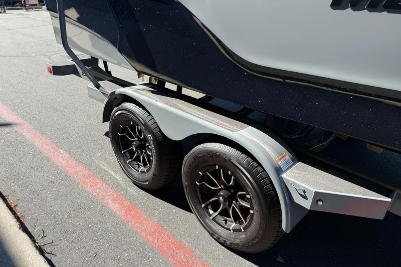 Slide: The Image of 2026 MasterCraft XT24 boat trailer with black alloy wheels on pavement. - 10