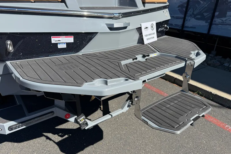 Slide: The Image of 2026 MasterCraft XT24 boat swim platform with foldable steps in sunlight. - 12