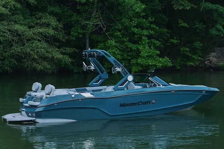 Slide: The Image of Manufacturer Provided Image: 2026 MasterCraft XT24 boat on a serene lake, surrounded by lush greenery. - 37