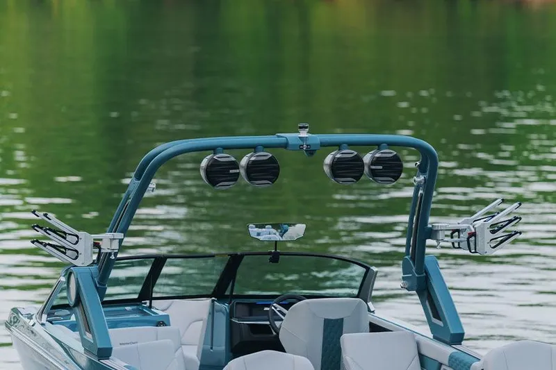 Slide: The Image of Manufacturer Provided Image: 2026 MasterCraft XT24 boat with speakers and wakeboard racks on a calm lake. - 4