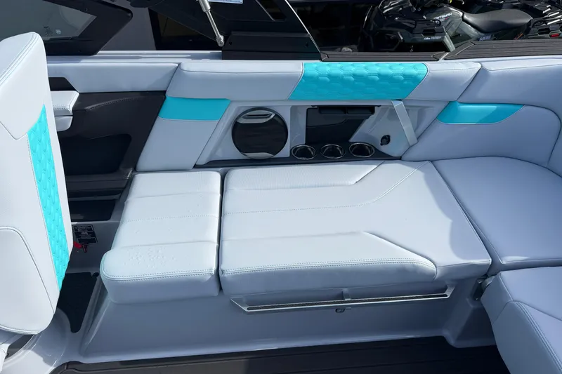 Slide: The Image of 2026 MasterCraft XT23 boat interior with white and turquoise seating, cup holders, and speaker. - 16