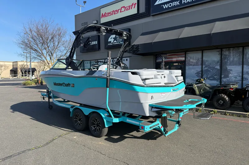 Slide: The Image of 2026 MasterCraft XT23 boat on trailer outside dealership, showcasing sleek design and vibrant color. - 2