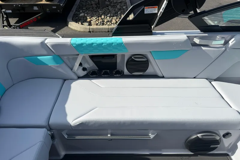Slide: The Image of 2026 MasterCraft XT23 boat interior with white and teal seating, cup holders, and speakers. - 20