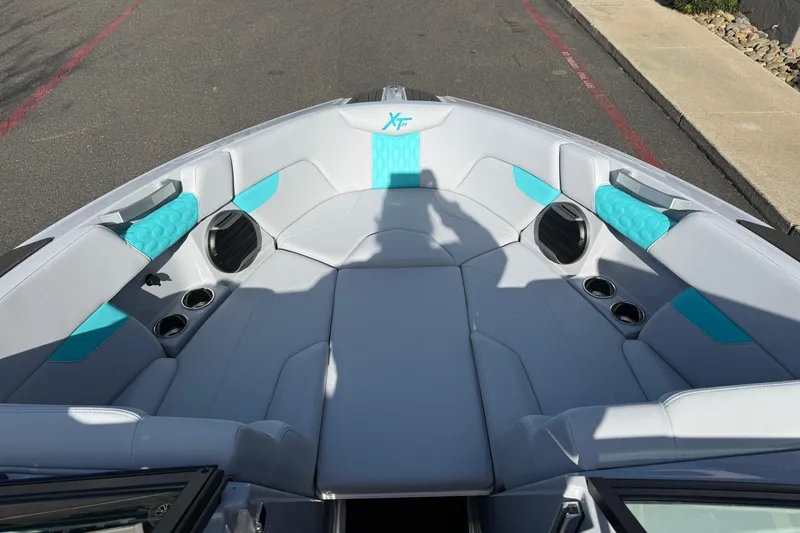 Slide: The Image of 2026 MasterCraft XT23 boat interior with gray and teal seating, cup holders, and speakers. - 24
