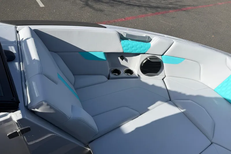 Slide: The Image of 2026 MasterCraft XT23 boat interior with gray and teal seating, cup holders, and speaker. - 25