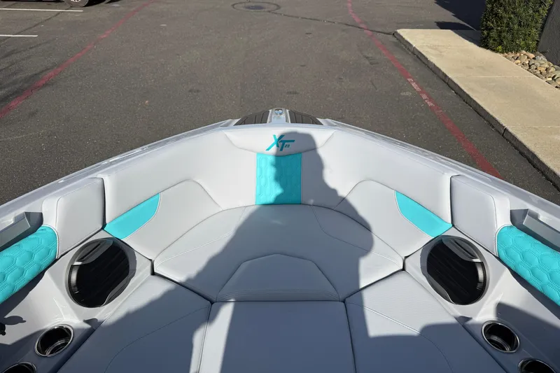 Slide: The Image of 2026 MasterCraft XT23 boat interior with white and turquoise seating, parked on pavement. - 26