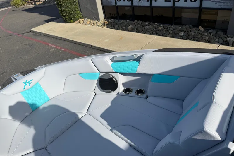Slide: The Image of 2026 MasterCraft XT23 boat interior with white and turquoise seating, cup holders, and speaker. - 27