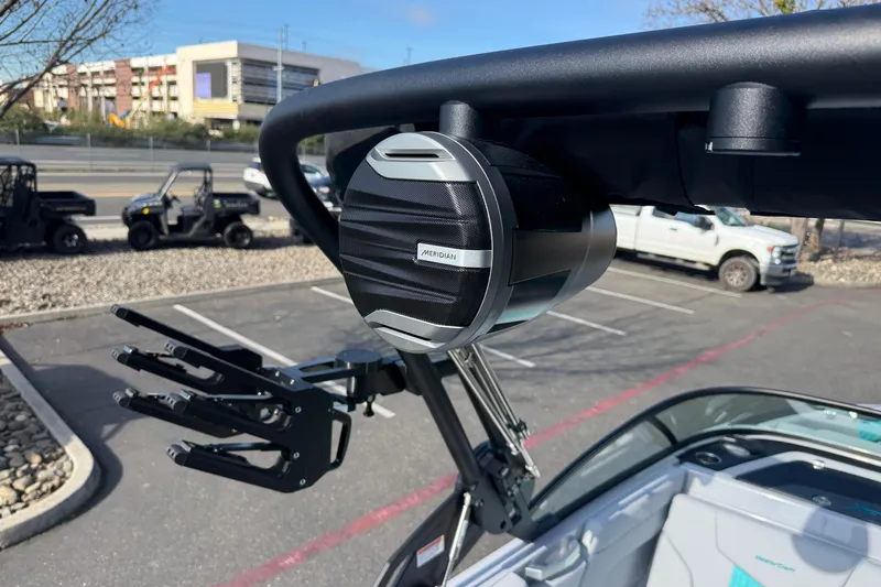 Slide: The Image of 2026 MasterCraft XT23 boat with mounted speaker and wakeboard rack in a parking lot. - 30