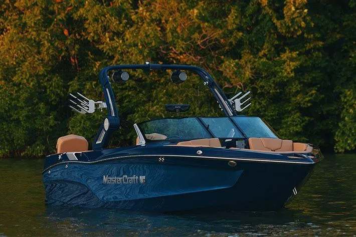 Slide: The Image of Manufacturer Provided Image: 2026 MasterCraft XT23 boat on water, surrounded by lush greenery. - 38