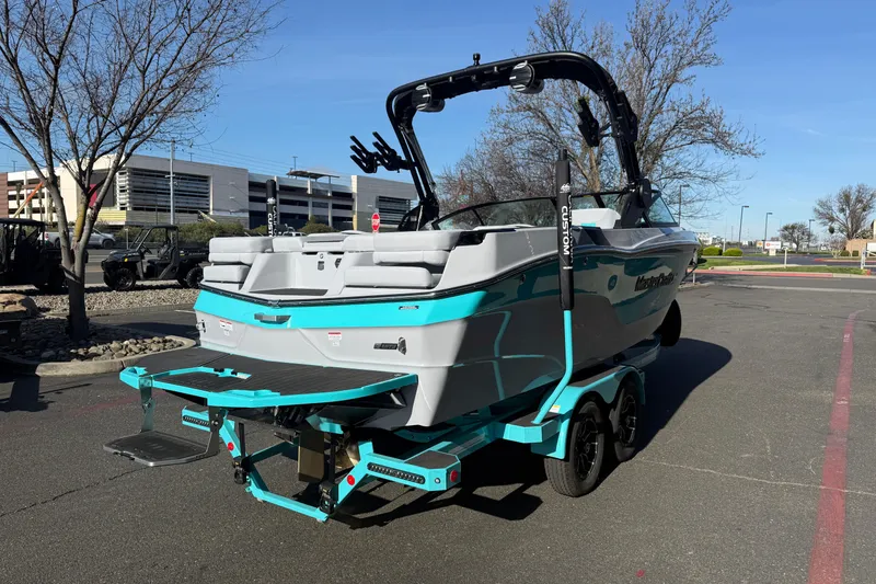 Slide: The Image of 2026 MasterCraft XT23 boat with vibrant teal accents parked outdoors. - 4