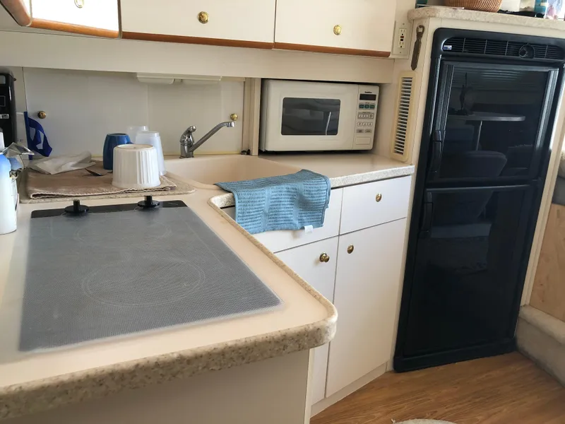 Slide: The Image of Kitchen area of a 1999 Silverton 351 Sedan yacht with microwave and fridge. - 13