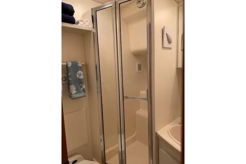 Slide: The Image of 1999 Silverton 351 Sedan bathroom with shower, towels, and seashell decor. - 17