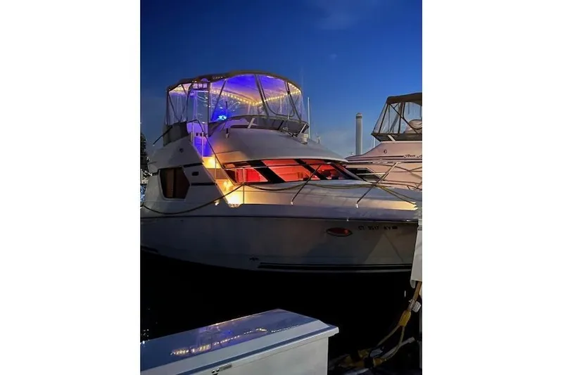 Slide: The Image of 1999 Silverton 351 Sedan yacht illuminated at night, docked with vibrant lights. - 3